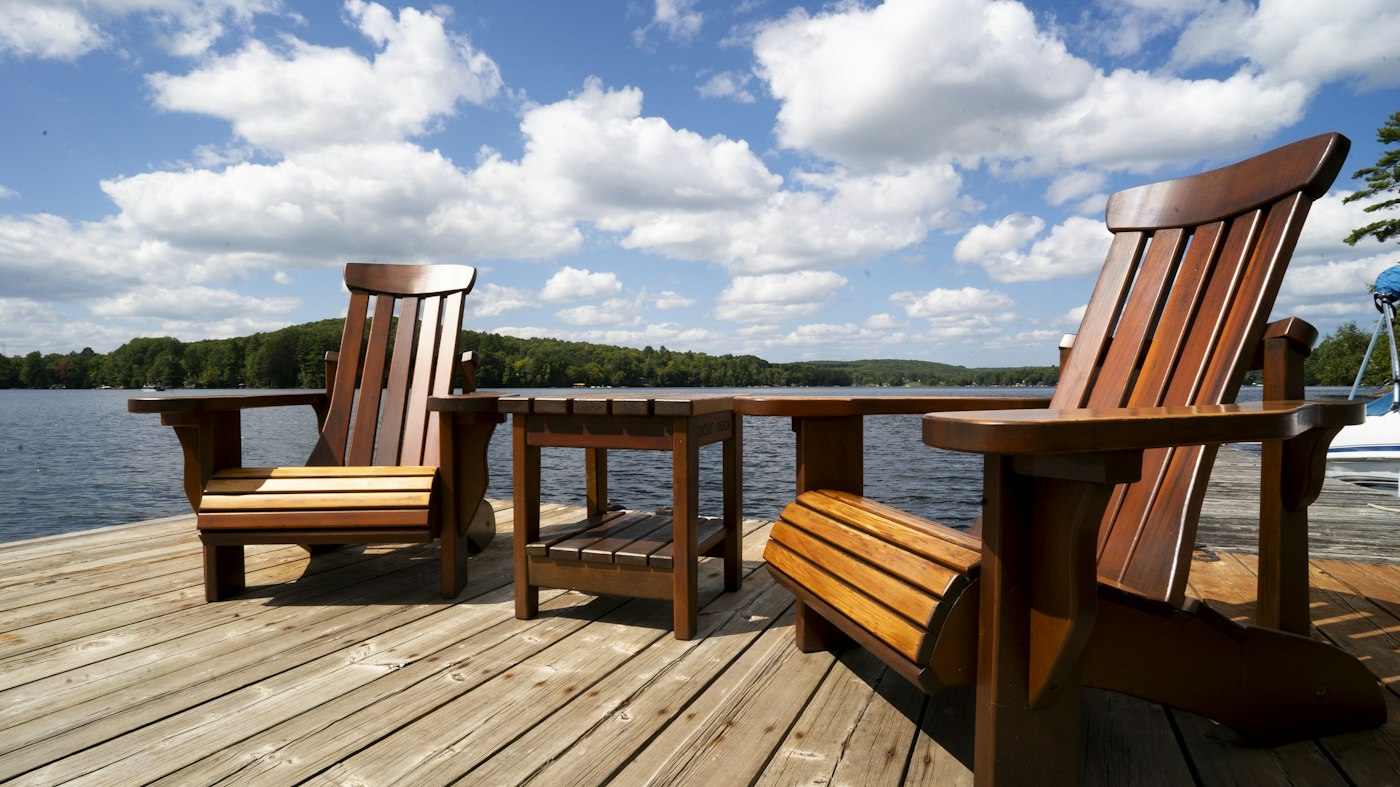 Two wooden chairs on a dock by the lake